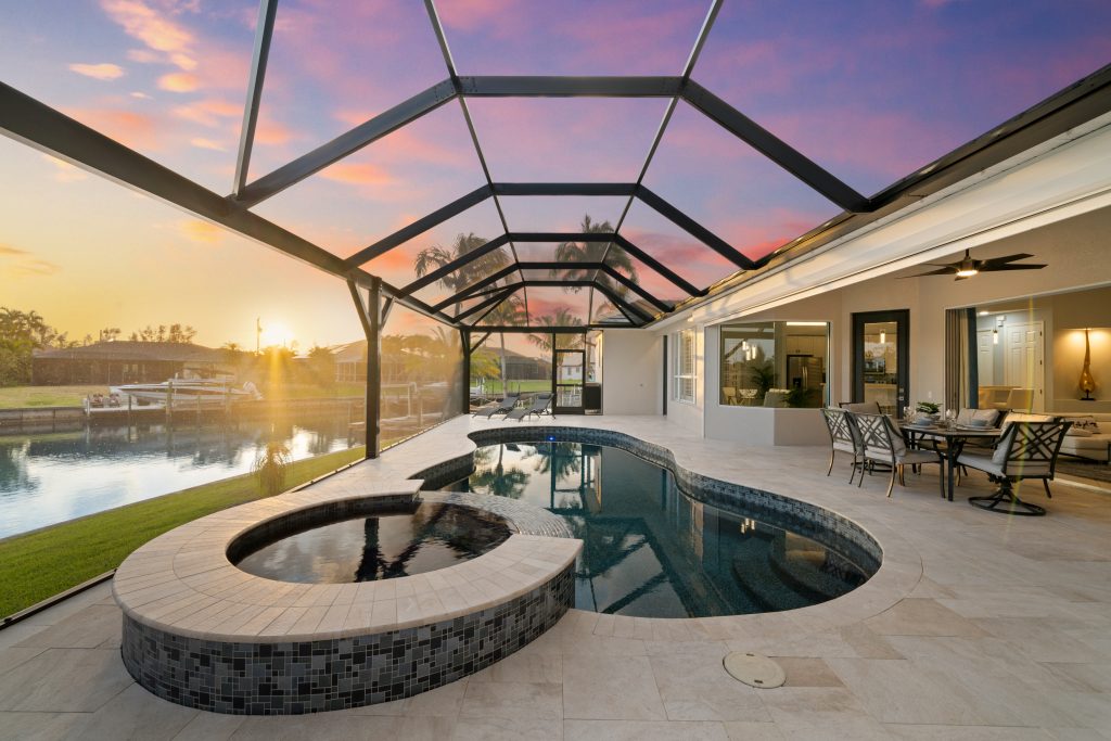 Überdachter Poolbereich der Villa in Cape Coral mit Whirlpool, Outdoor-Küche und Blick auf den Sonnenuntergang am Kanal
